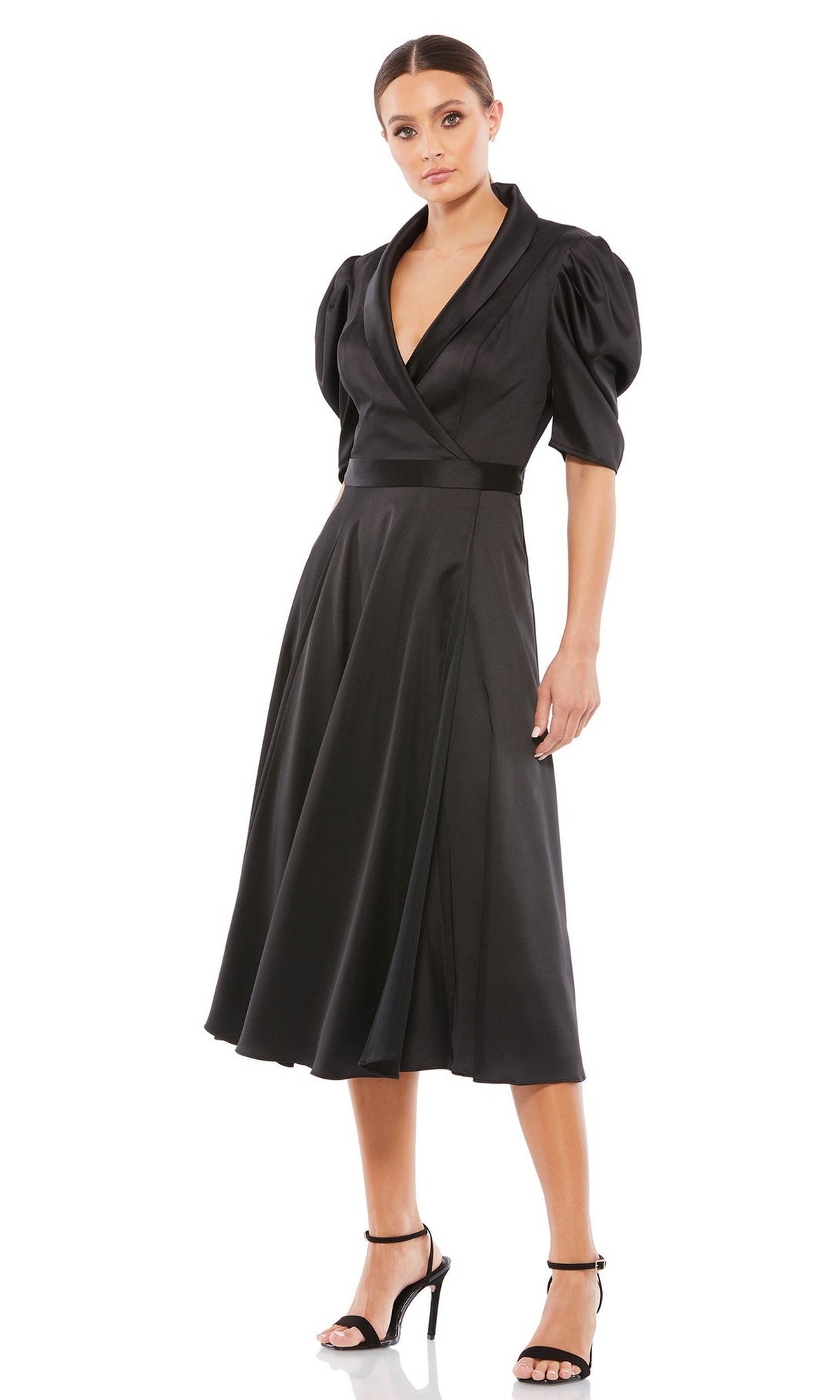 A woman in the Mac Duggal 2628 Short Sleeve Wedding Guest Dress and black high heels stands against a white background.